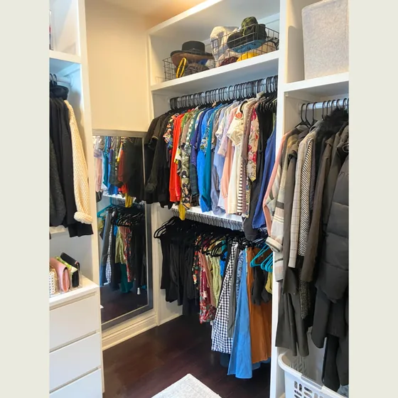 Walk-in closet with hanging clothes grouped by type and color
